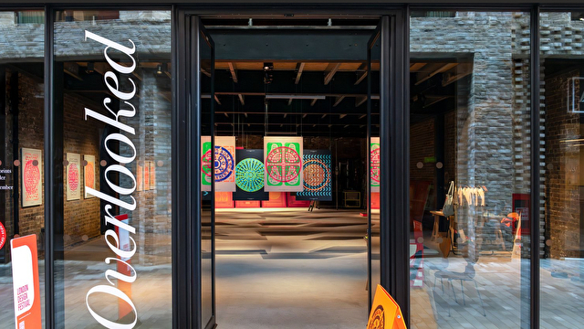 A glass storefront with large white text reading “Overlooked” displayed vertically on the left door.