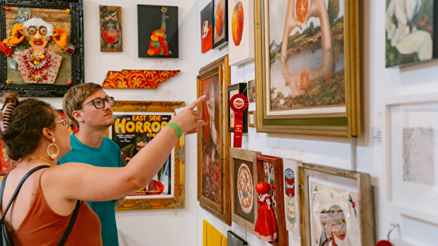 a man and woman view framed artwork hanging on the gallery wall