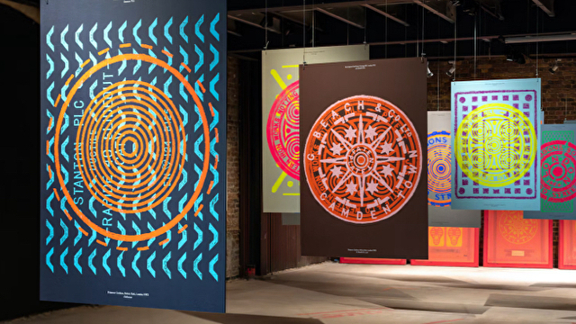Colourful circular prints hang in a gallery space.